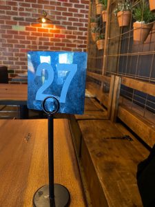 Number 27 on a table number in a cafe with a red brick wall